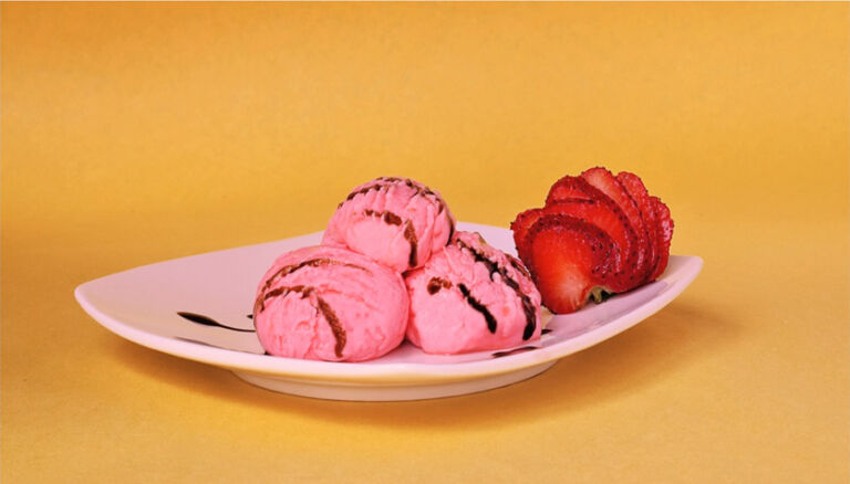 Helado de fresa en un plato y decorado con fruta natural