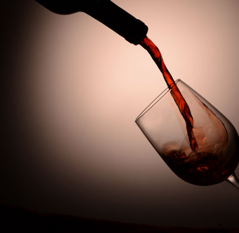 Vino tinto servido a contra luz en una copa de cristal