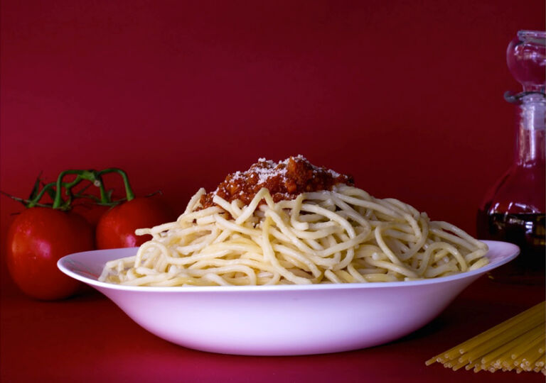 Plato de espagueti decorado con carne y queso parmesano